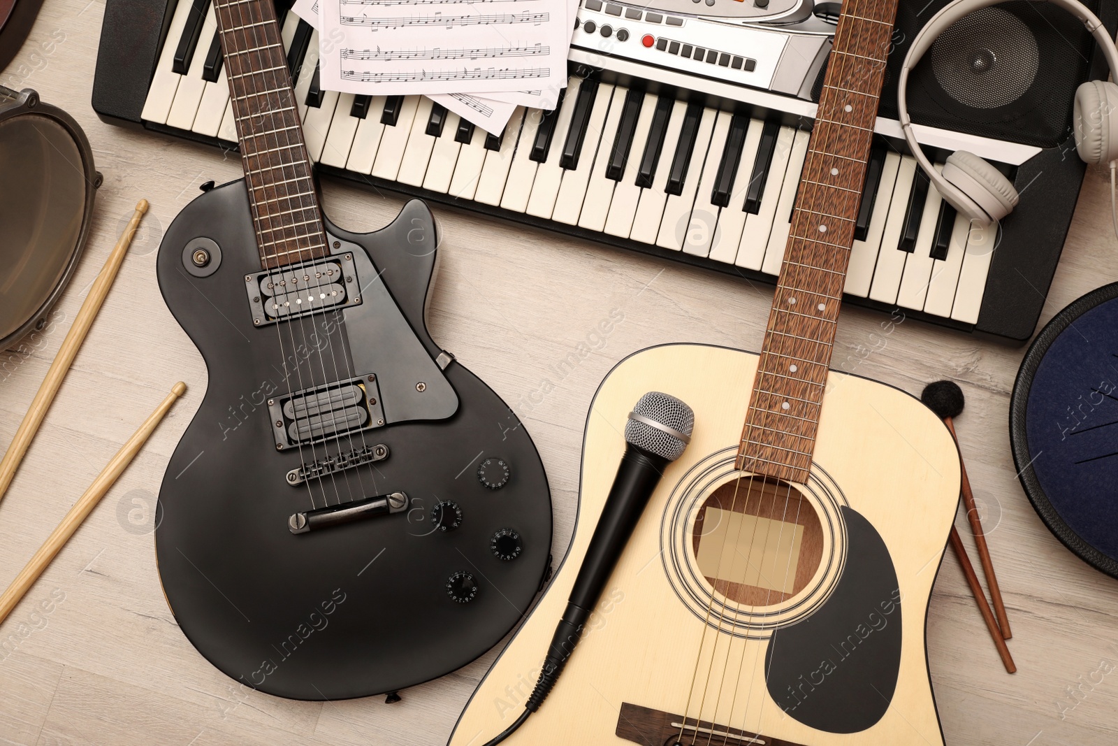 Photo of Different musical instruments, headphones and microphone on wooden background, flat lay