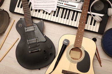 Different musical instruments, headphones and microphone on wooden background, flat lay