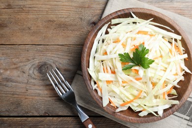 Photo of Fresh cabbage salad served on wooden table, flat lay