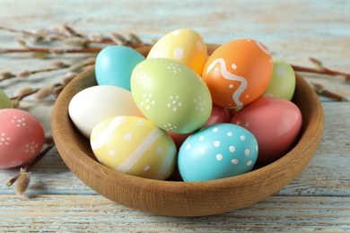 Photo of Plate with painted Easter eggs on wooden table