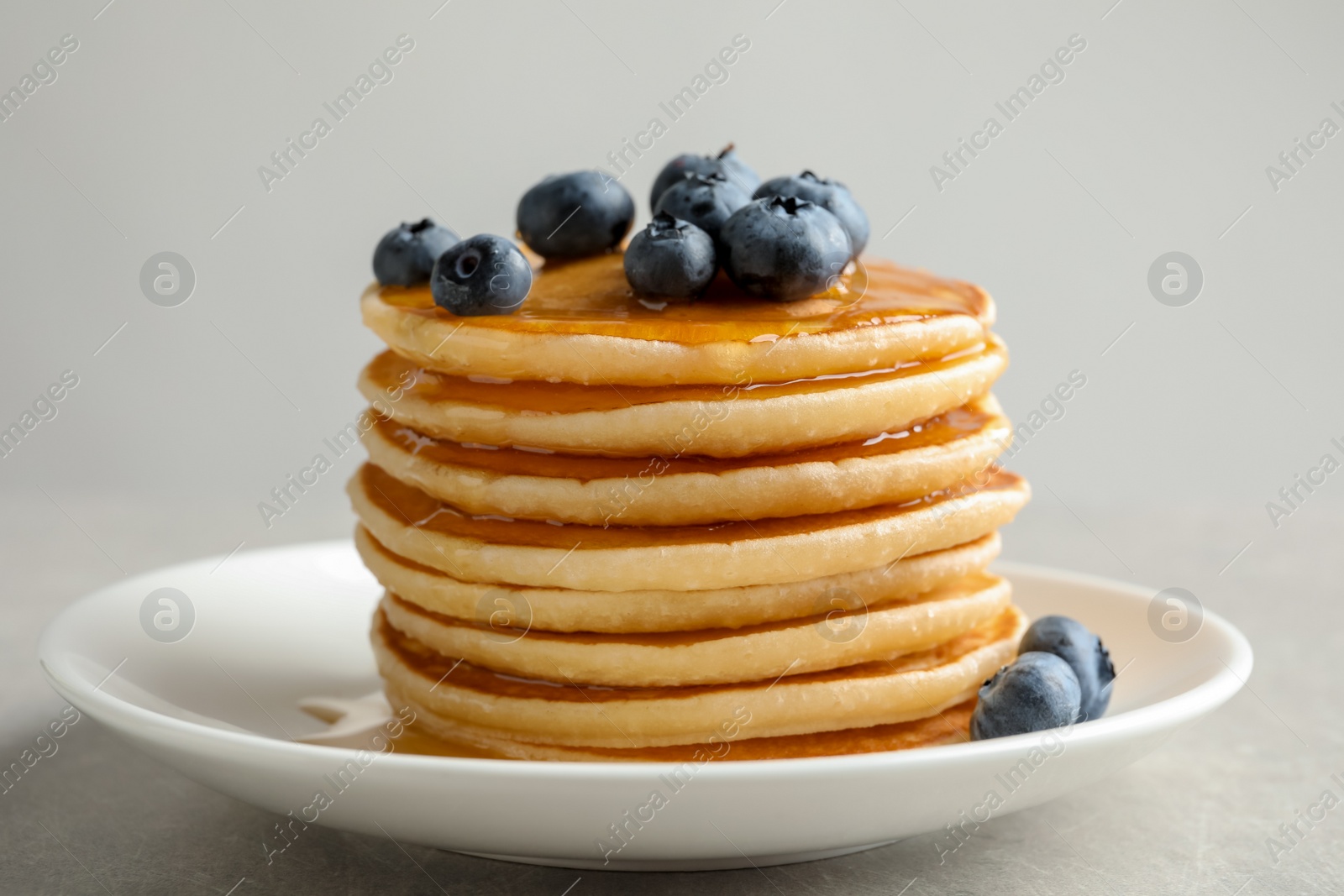 Photo of Plate with pancakes and berries on grey background, closeup