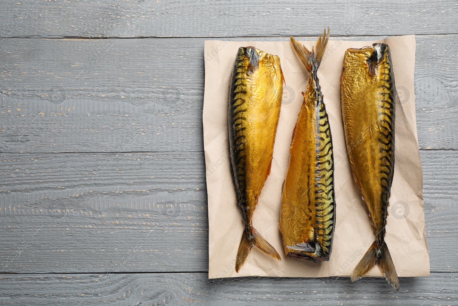 Photo of Tasty smoked fish on light grey wooden table, top view. Space for text