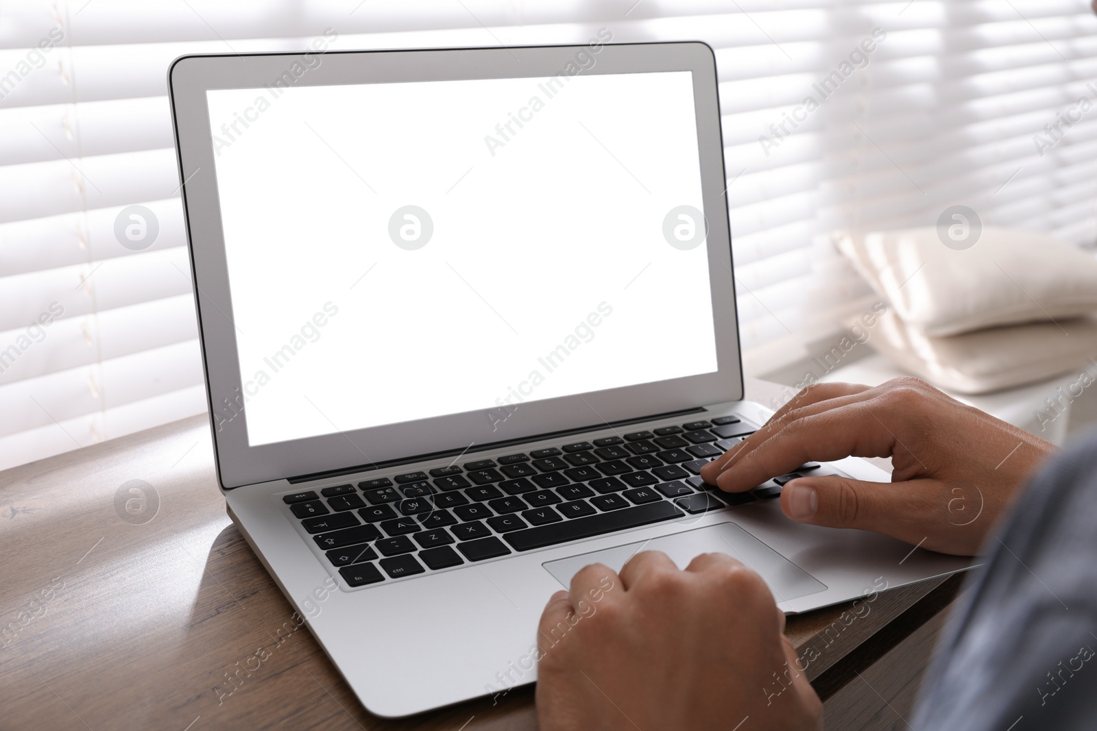 Photo of Man with modern laptop at wooden table indoors, closeup. Space for design