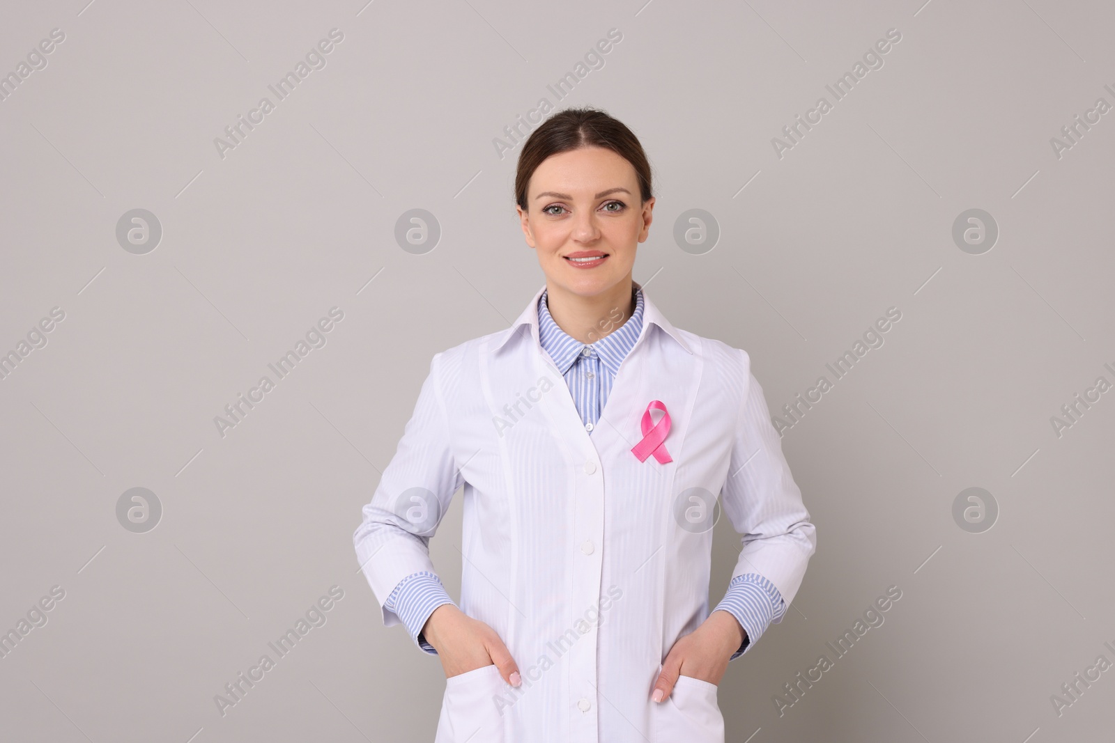 Photo of Mammologist with pink ribbon on grey background. Breast cancer awareness