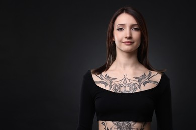 Photo of Portrait of beautiful tattooed woman on black background. Space for text