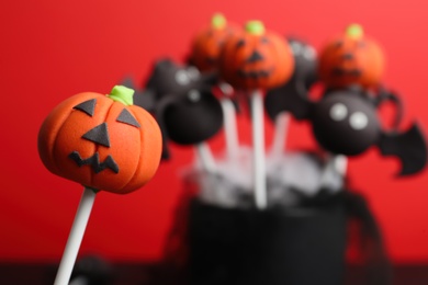 Photo of Delicious Halloween themed cake pops on red background, closeup. Space for text