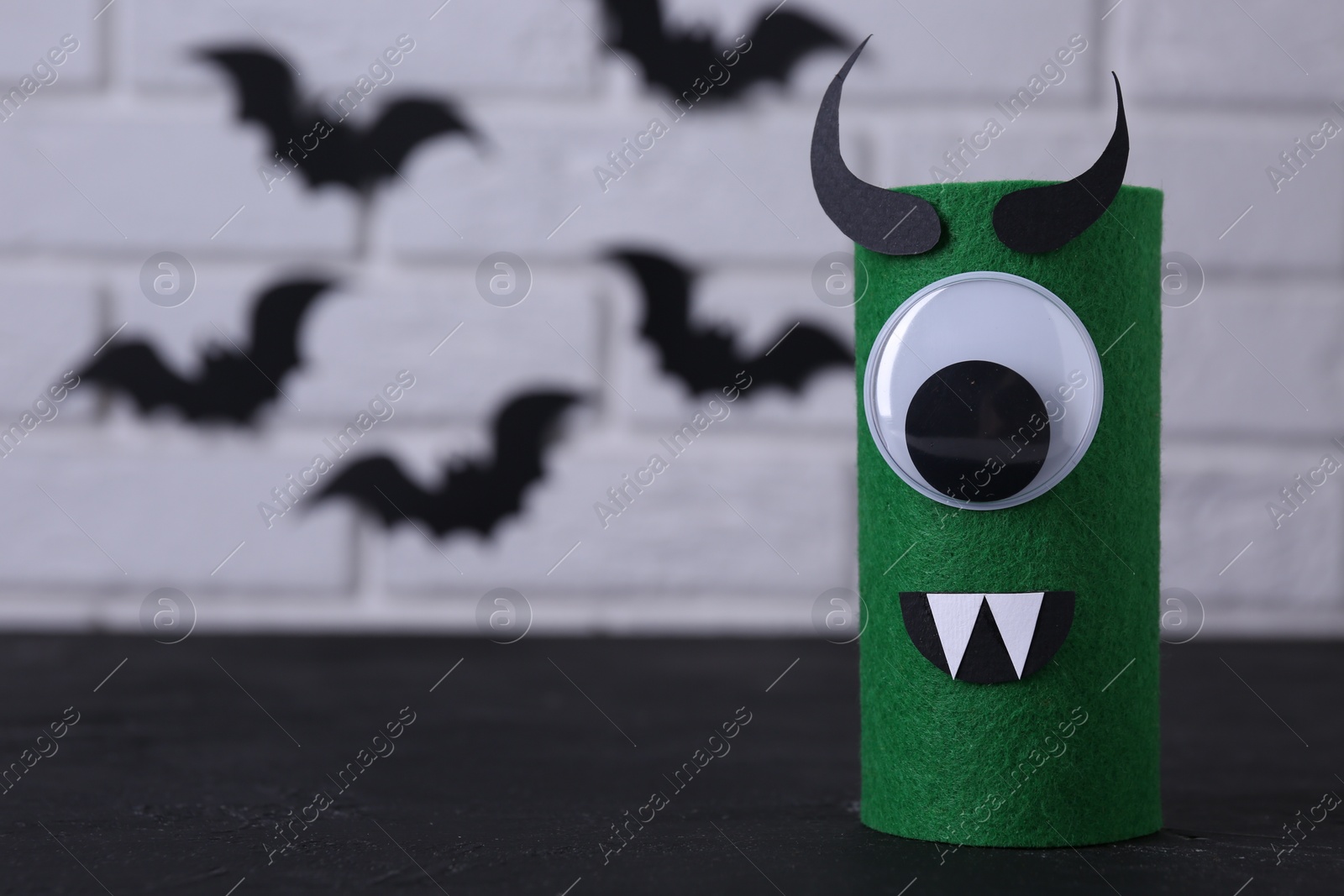 Photo of Spooky monster on black table, space for text. Handmade Halloween decoration