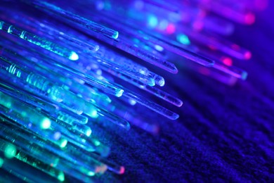 Photo of Optical fiber strands transmitting different color lights on dark background, macro view