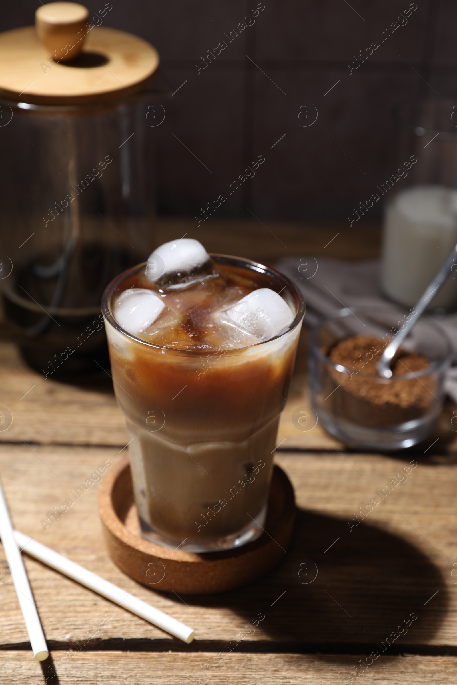 Photo of Refreshing iced coffee in glass and straws on wooden table