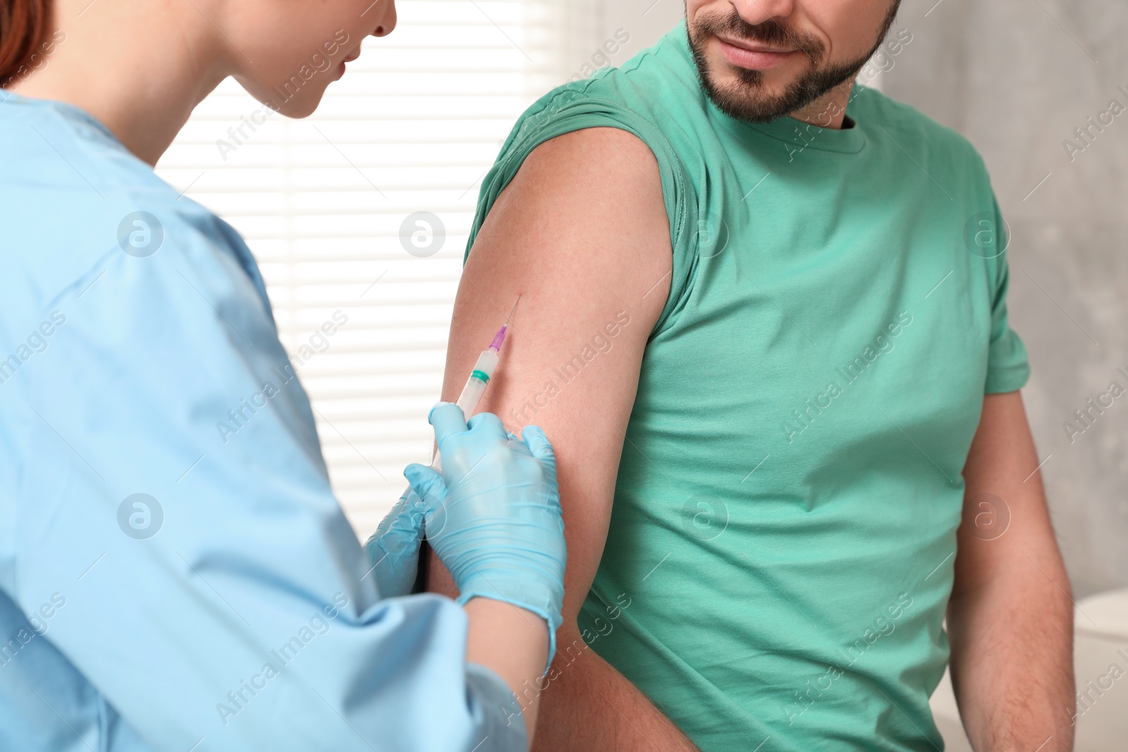 Photo of Doctor giving hepatitis vaccine to patient in clinic, closeup