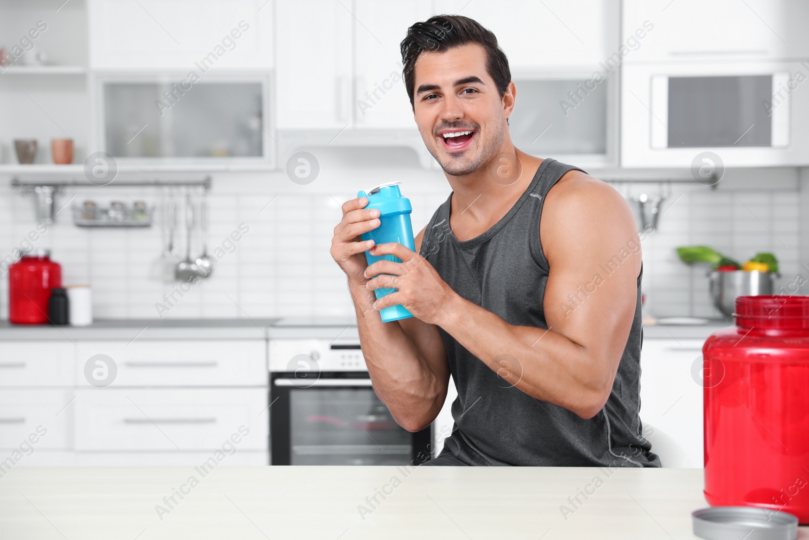 Photo of Young athletic man with protein shake powder in kitchen, space for text