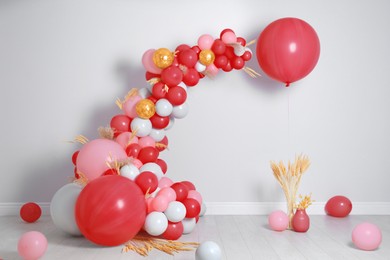 Image of Balloon garland near white wall in room. Festive decor