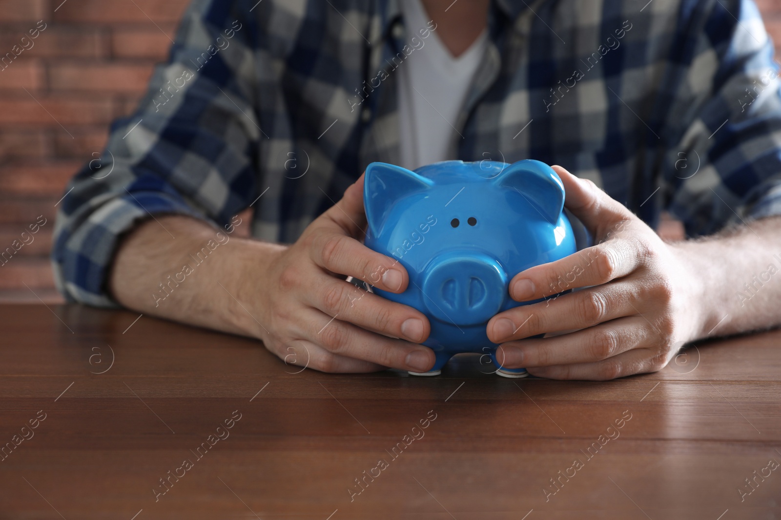 Photo of Man with piggy bank at wooden table, closeup