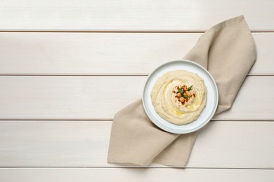Photo of Tasty hummus with garnish served on white wooden table, top view. Space for text