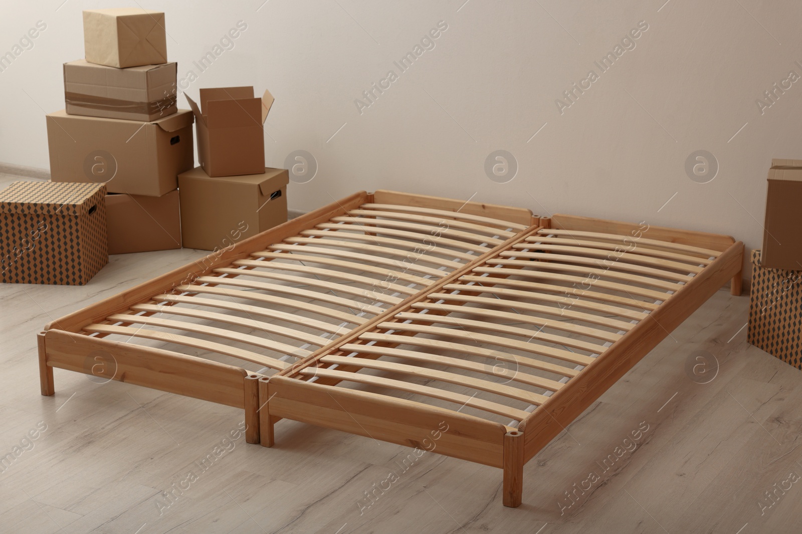 Photo of Wooden bed frame and cardboard boxes on floor in room