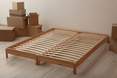 Photo of Wooden bed frame and cardboard boxes on floor in room