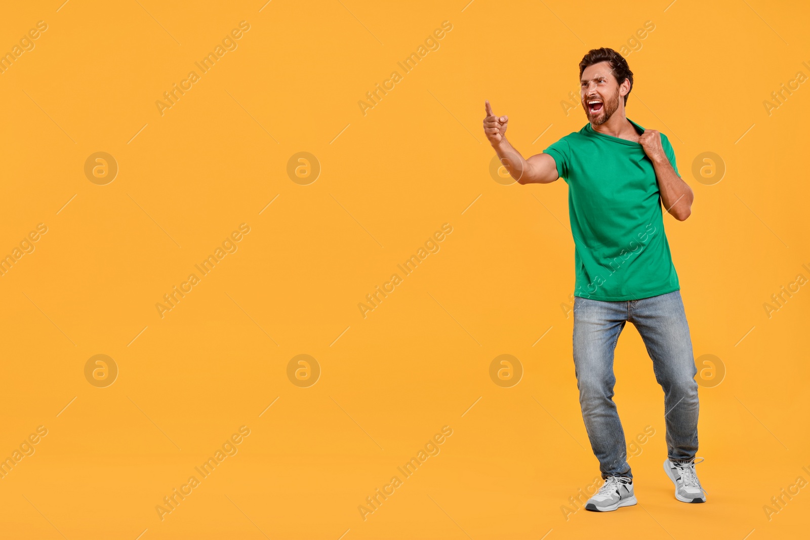 Photo of Emotional sports fan celebrating on orange background. Space for text