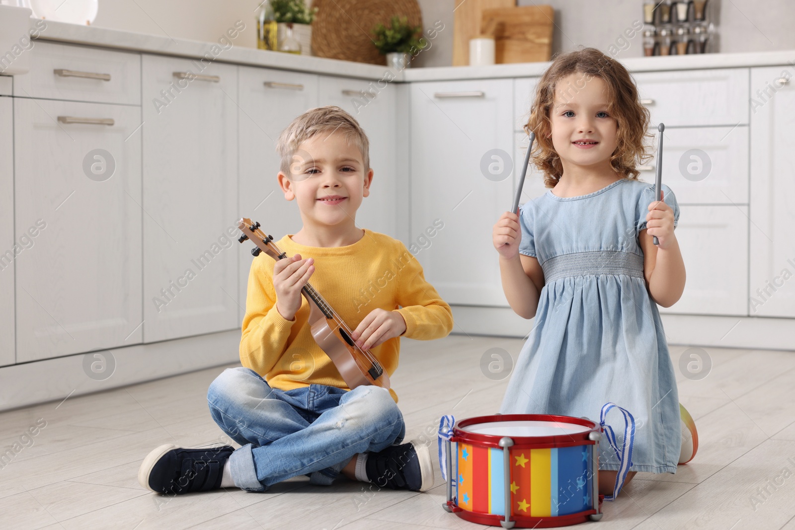 Photo of Little children playing toy musical instruments in kitchen