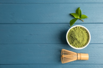 Photo of Matcha tea in bowl, whisk and green leaves on wooden table, top view