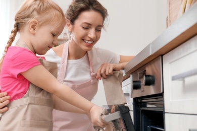 Mother and her daughter baking food in oven at home