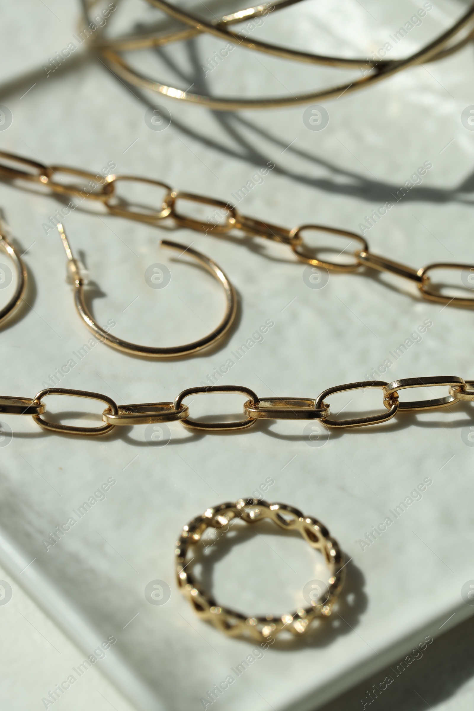 Photo of Metal chain and other different accessories on white dish, closeup. Luxury jewelry