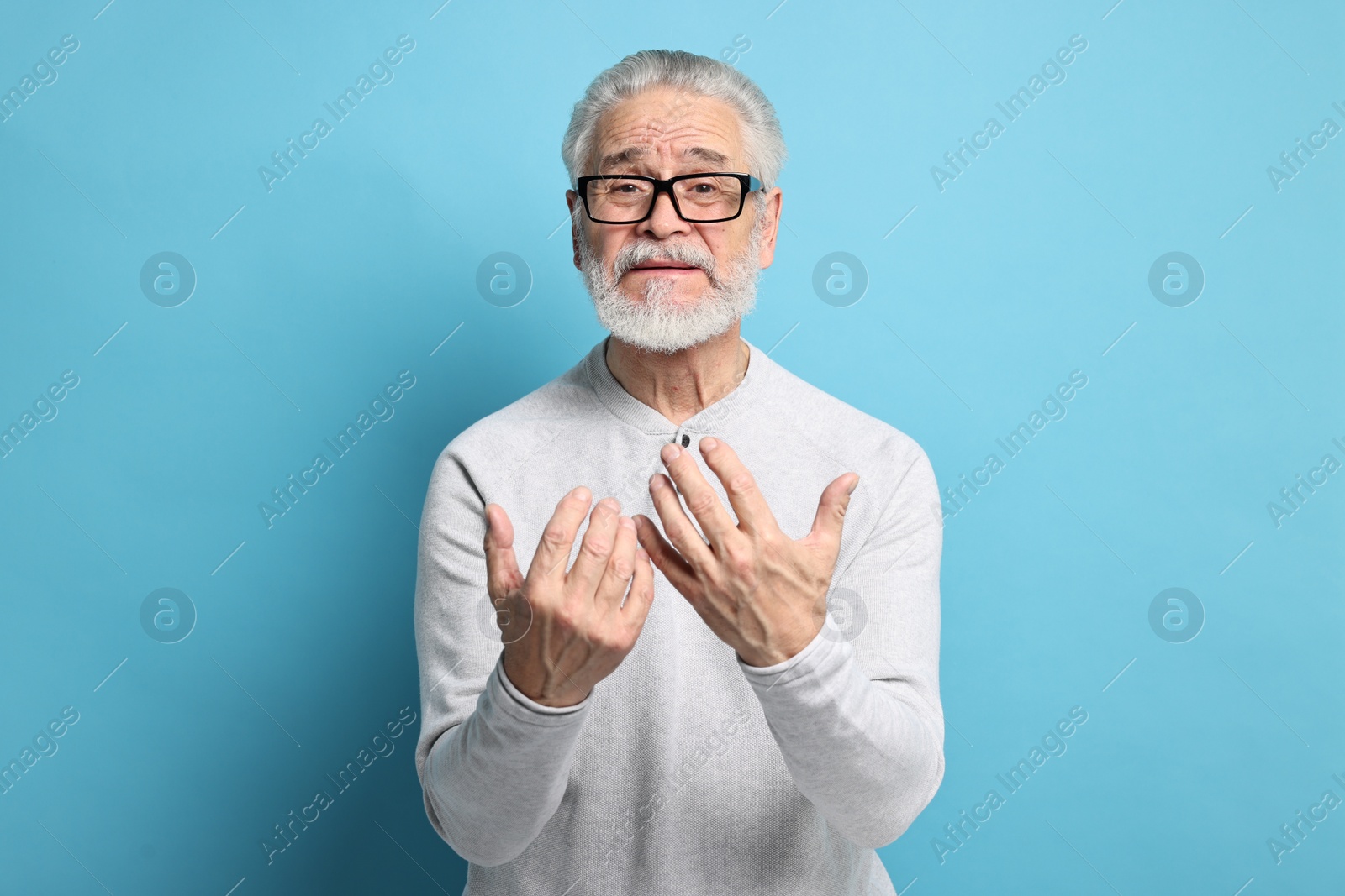 Photo of Arthritis symptoms. Man suffering from pain in hands on light blue background