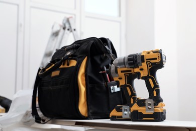 Pair of modern electric power drills and tool bag indoors