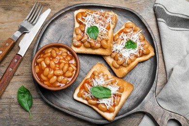 Toasts with delicious canned beans on wooden table, flat lay
