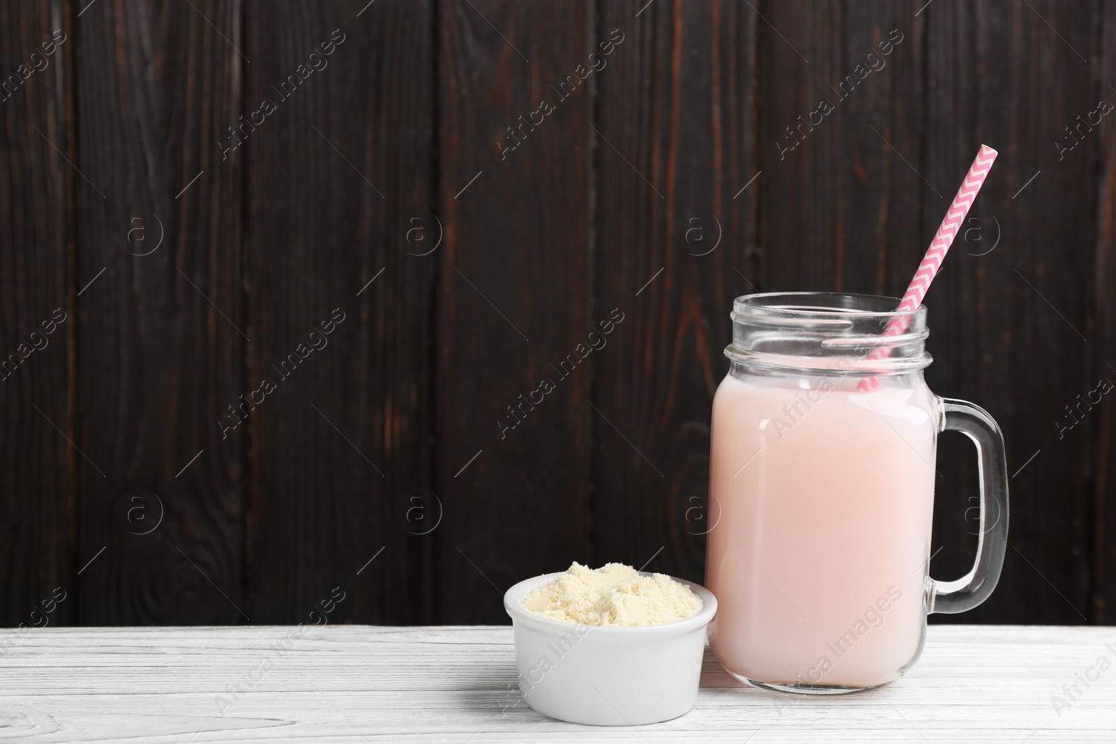 Photo of Protein shake and powder on white wooden table, space for text