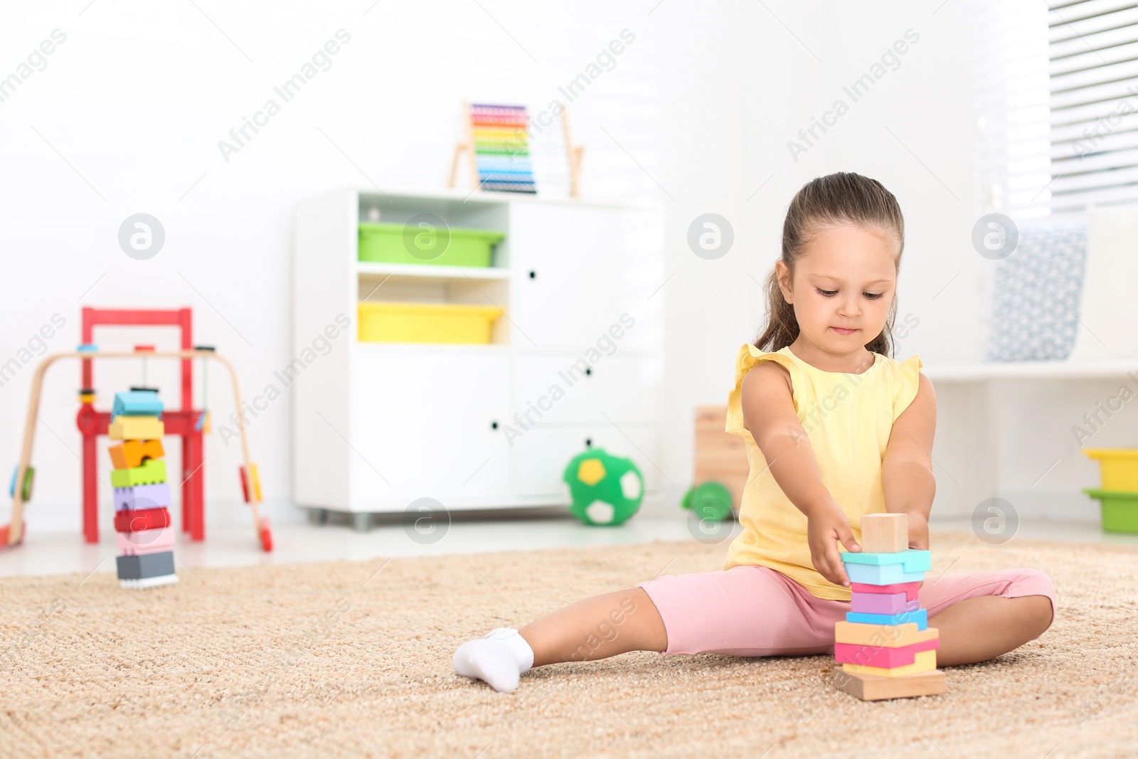 Photo of Cute little girl playing with toy on floor at home, space for text