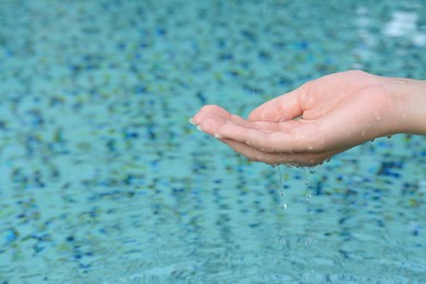 Girl holding water in hand above pool, closeup. Space for text