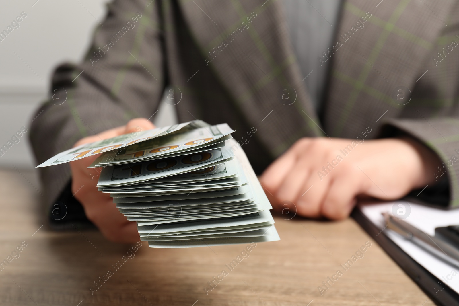 Photo of Money exchange. Woman holding dollar banknotes at wooden table, closeup