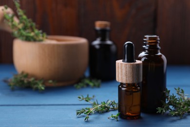 Thyme essential oil on light blue wooden table, space for text