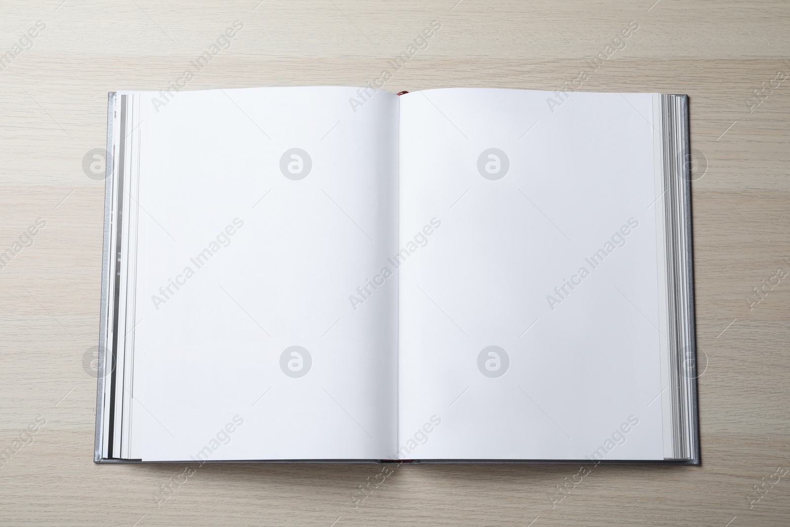 Photo of Open book with hard cover on wooden table, top view