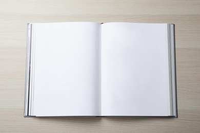 Open book with hard cover on wooden table, top view