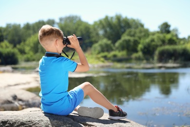 Photo of Little boy with binoculars outdoors. Summer camp