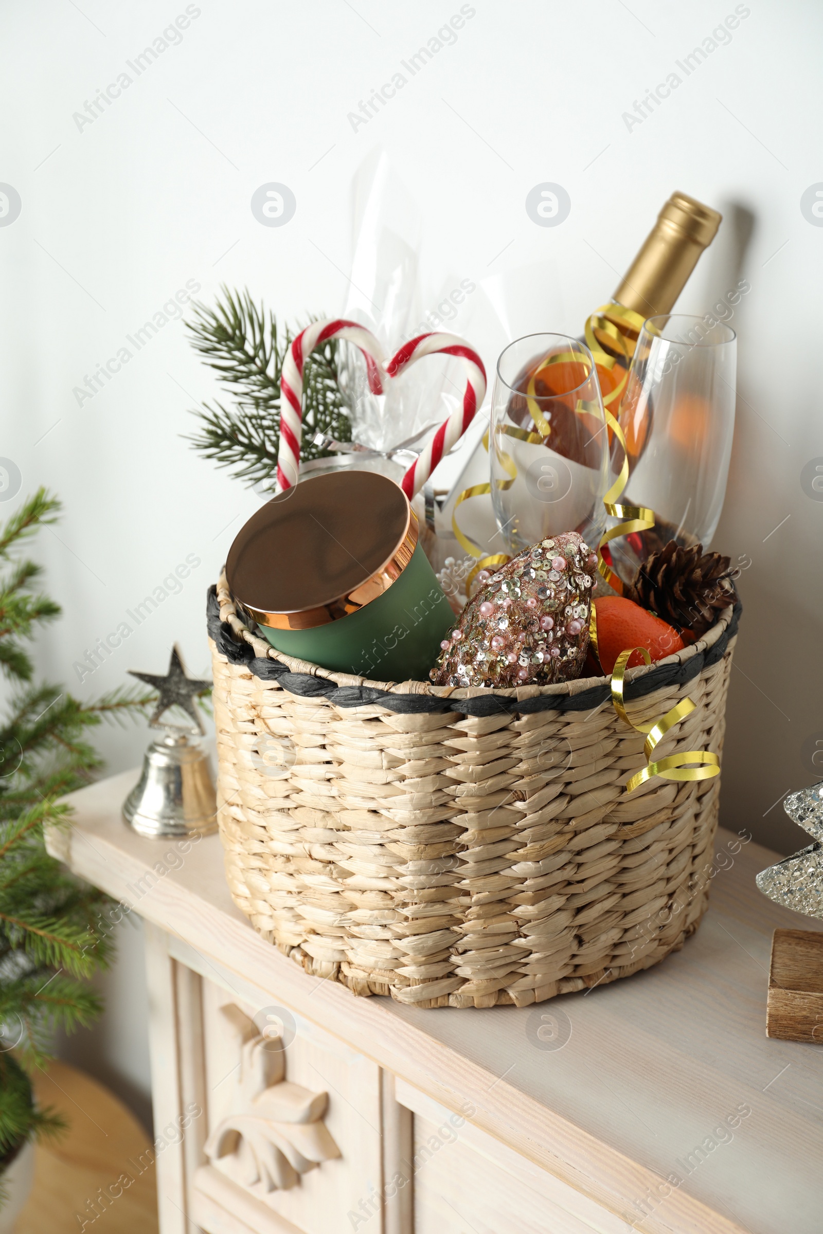 Photo of Wicker basket with gift set and Christmas decor on shelf