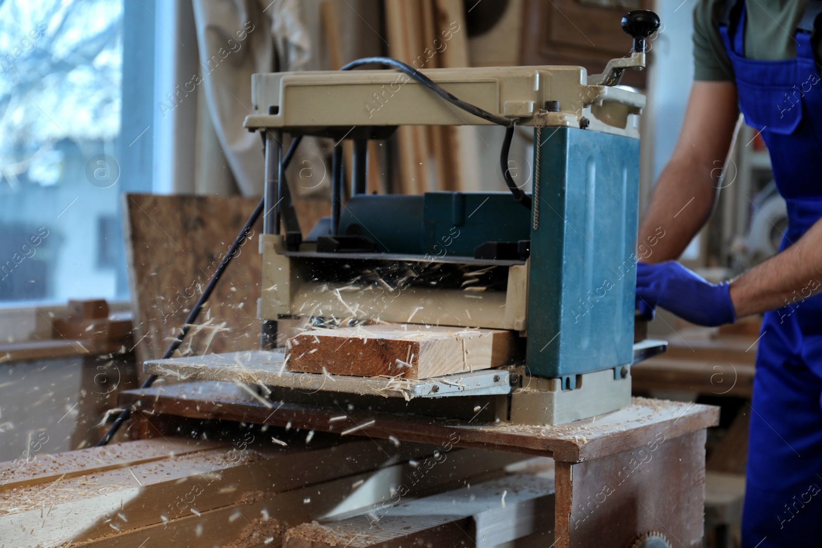 Photo of Professional carpenter working with grinding machine in shop, closeup