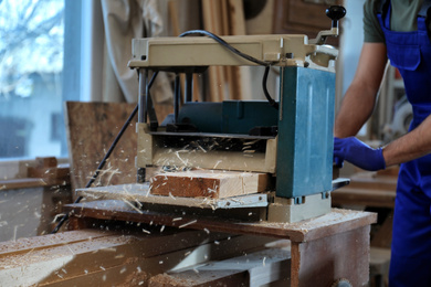 Photo of Professional carpenter working with grinding machine in shop, closeup