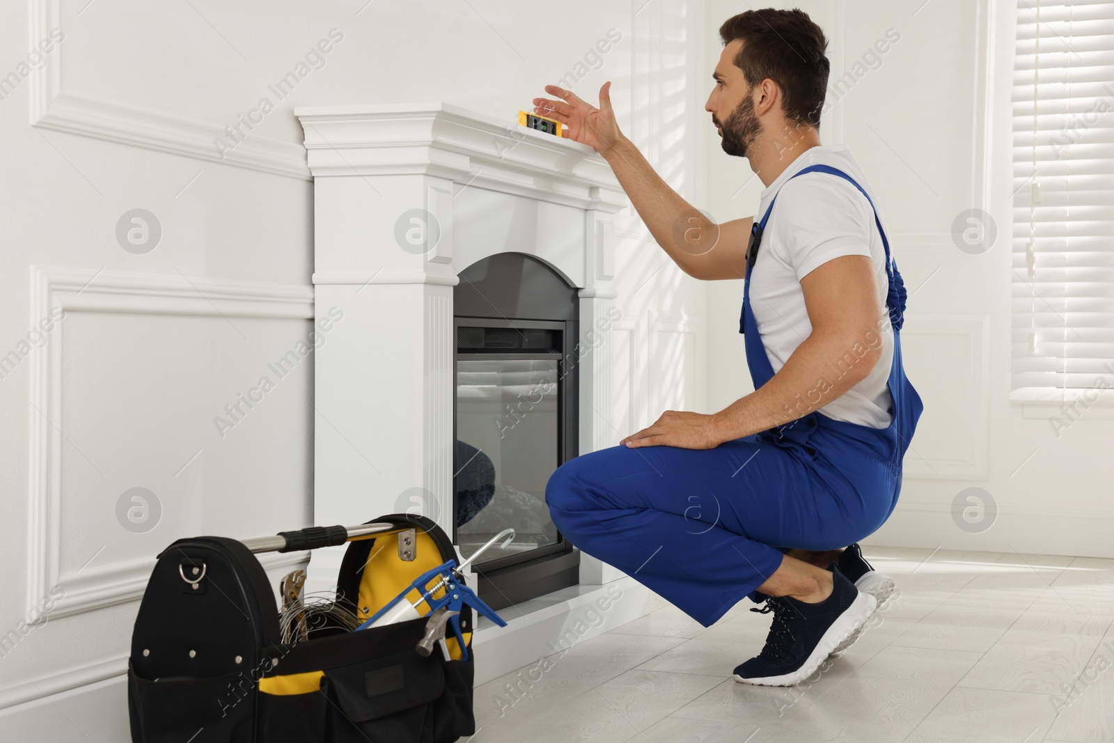 Photo of Professional technician installing electric fireplace in room