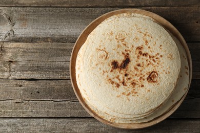 Photo of Stack of tasty homemade tortillas on wooden table, top view. Space for text