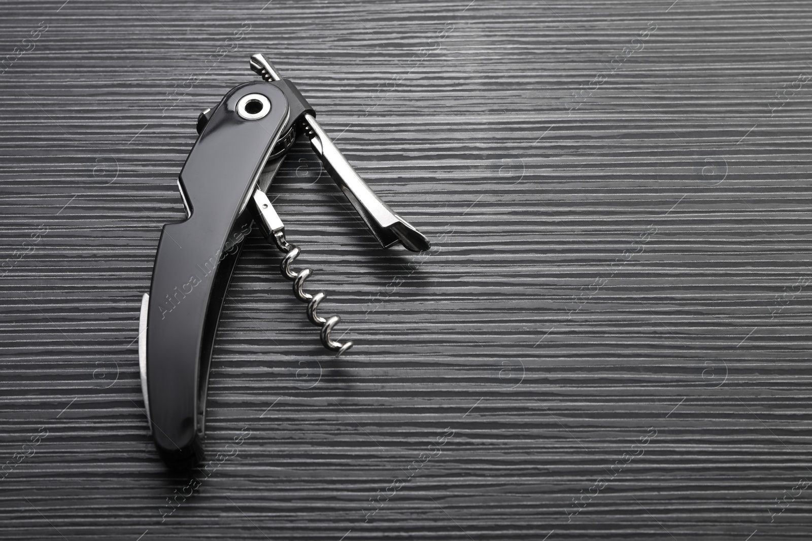 Photo of One corkscrew (sommelier knife) on black wooden table, top view. Space for text