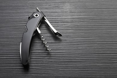 Photo of One corkscrew (sommelier knife) on black wooden table, top view. Space for text