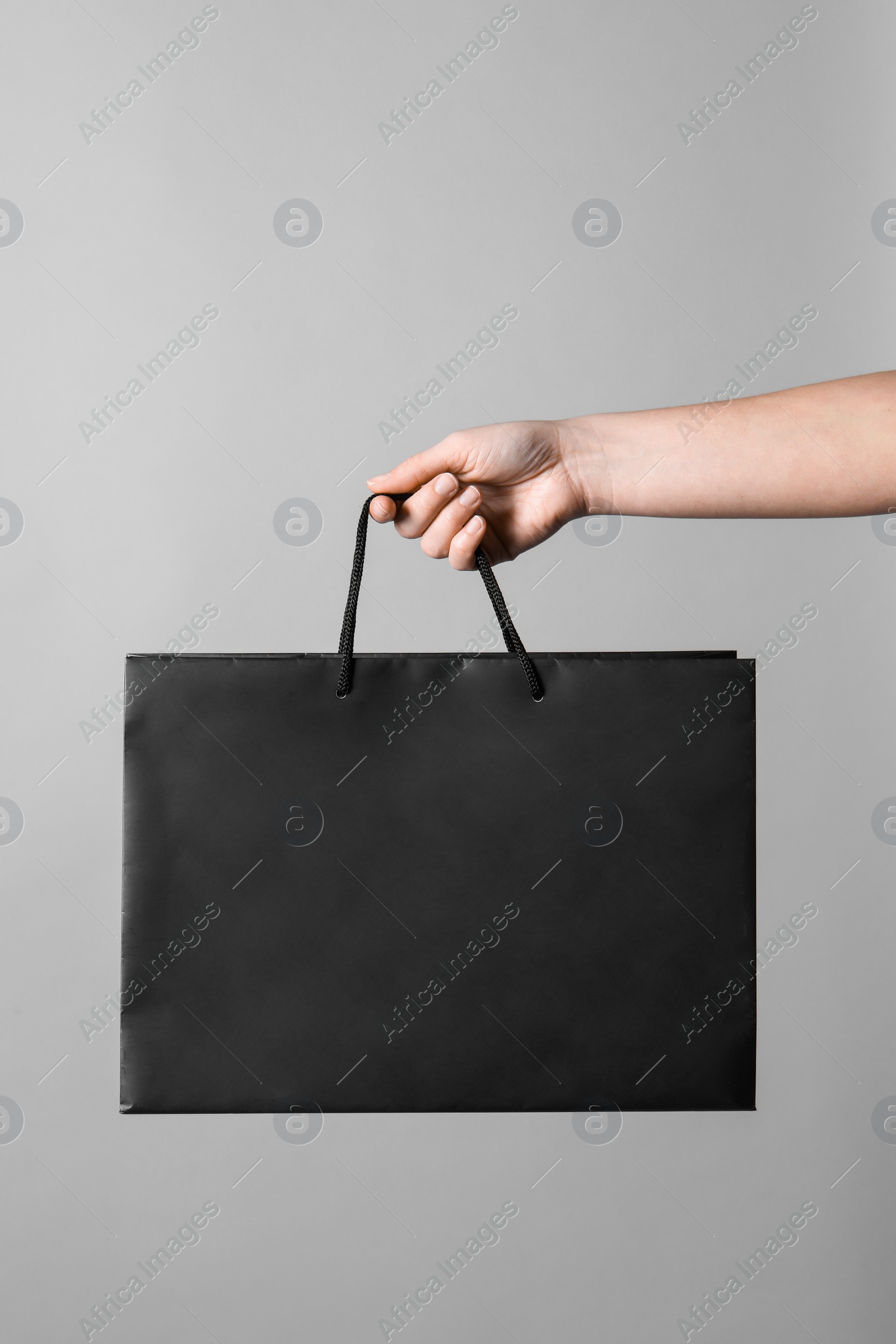 Photo of Woman holding paper shopping bag on grey background, closeup