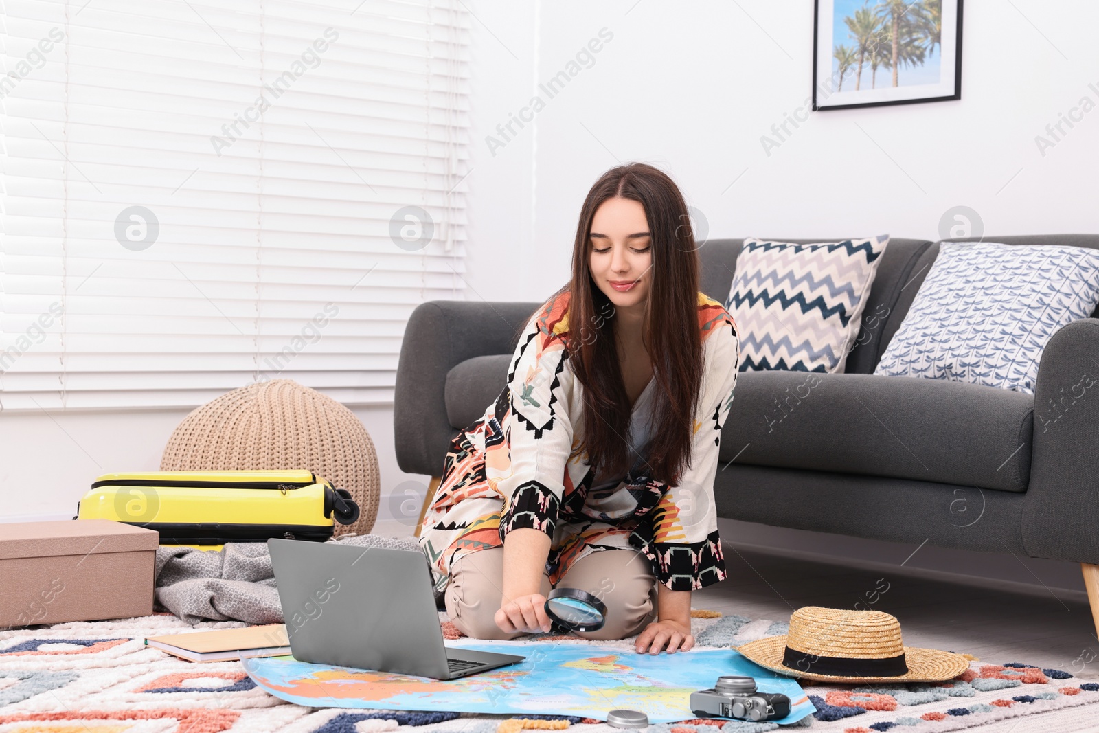 Photo of Travel blogger with magnifying glass and map planning trip at home