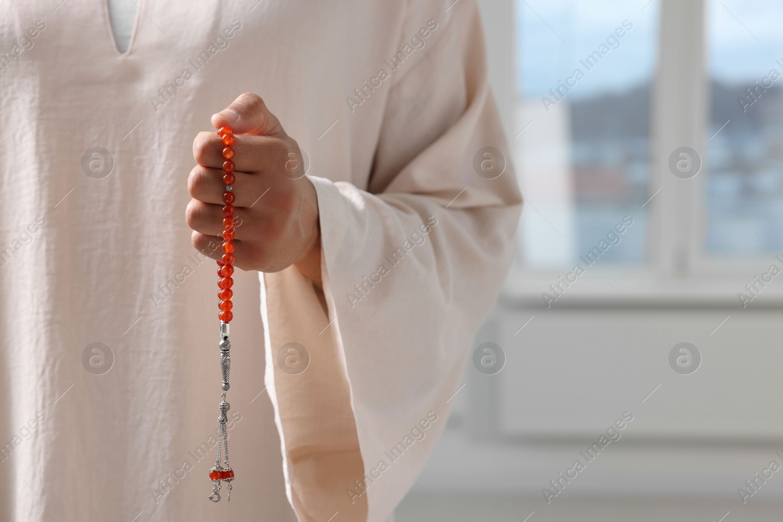 Photo of Muslim man with misbaha indoors, closeup. Space for text