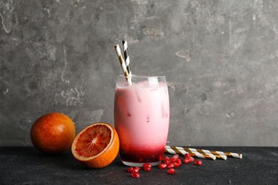 Photo of Glass of tropical cocktail with ice cubes and fruit on table