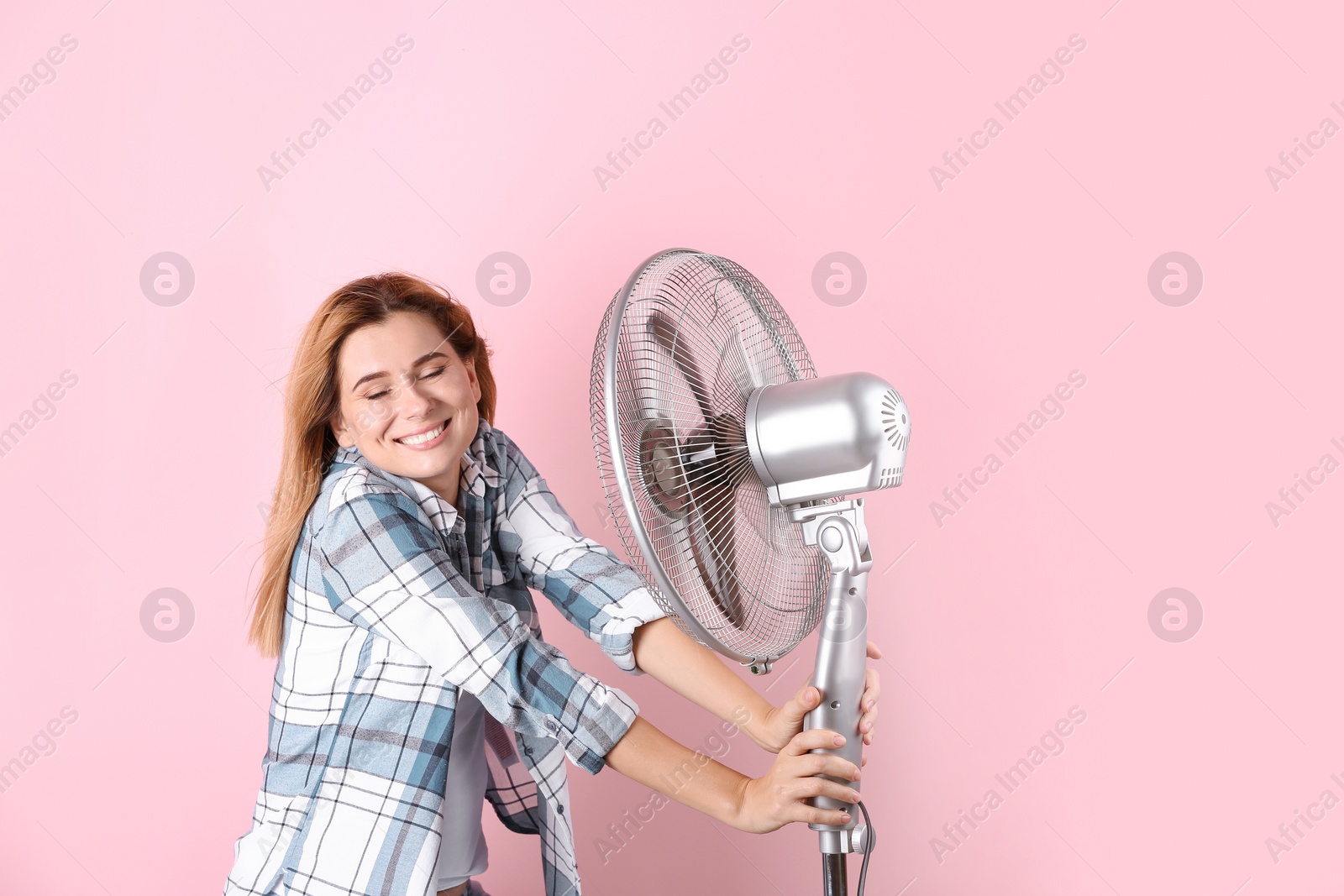 Photo of Woman refreshing from heat in front of fan on color background