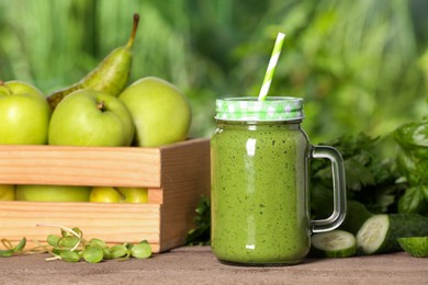 Photo of Mason jar of fresh green smoothie and ingredients on wooden table outdoors