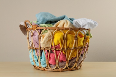Photo of Wicker laundry basket with towels on wooden table